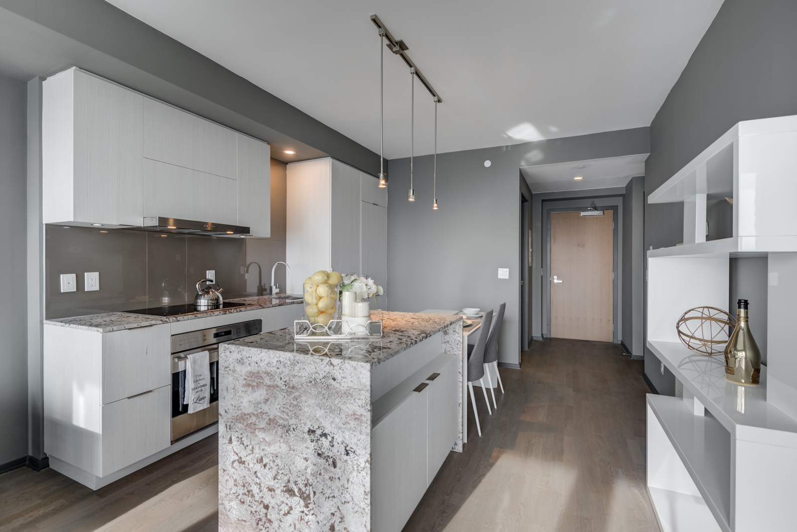 Modern kitchen of 1 Bloor St E Unit 4305 with granite counters, island, pendant lights and wooden cabinets.
