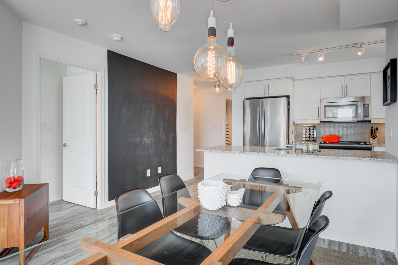 Close up of pendent light-bulbs hanging above dining table and blackboard wall in 400 Adelaide St E Unit 704 in Moss Park.