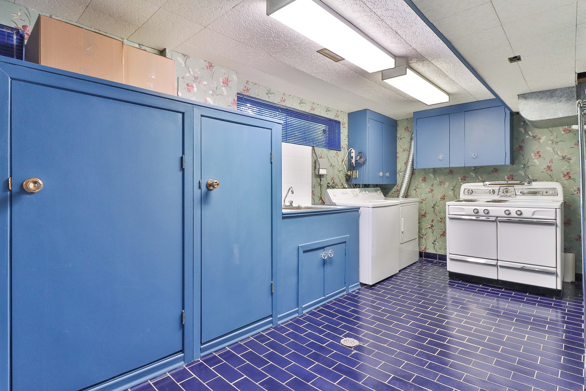 Chic laundry room with dark blue ceramic tiles and light blue cabinets.