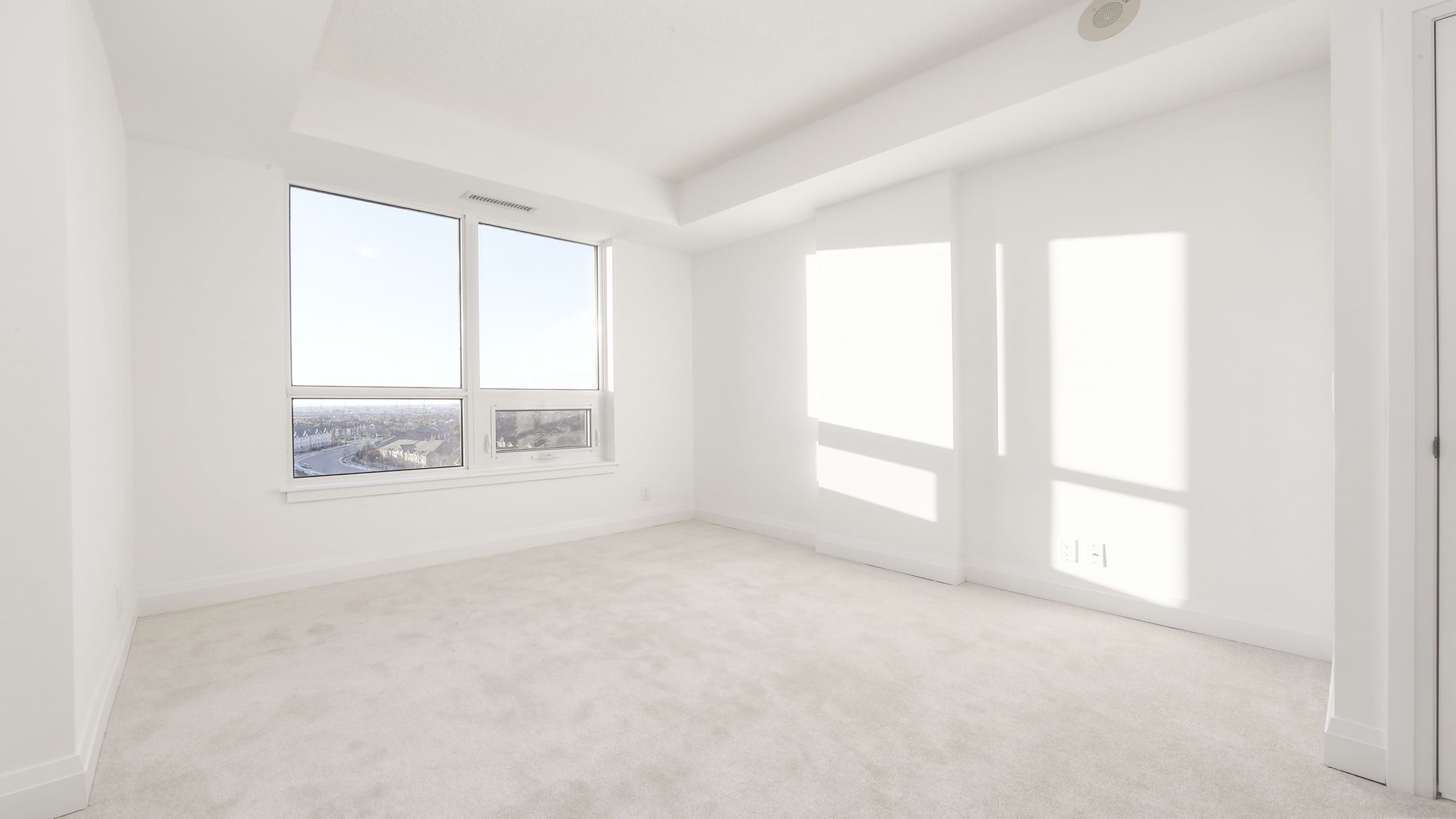 Bedroom photo showing windows and sunlight. The white carpet almost blends into the walls.