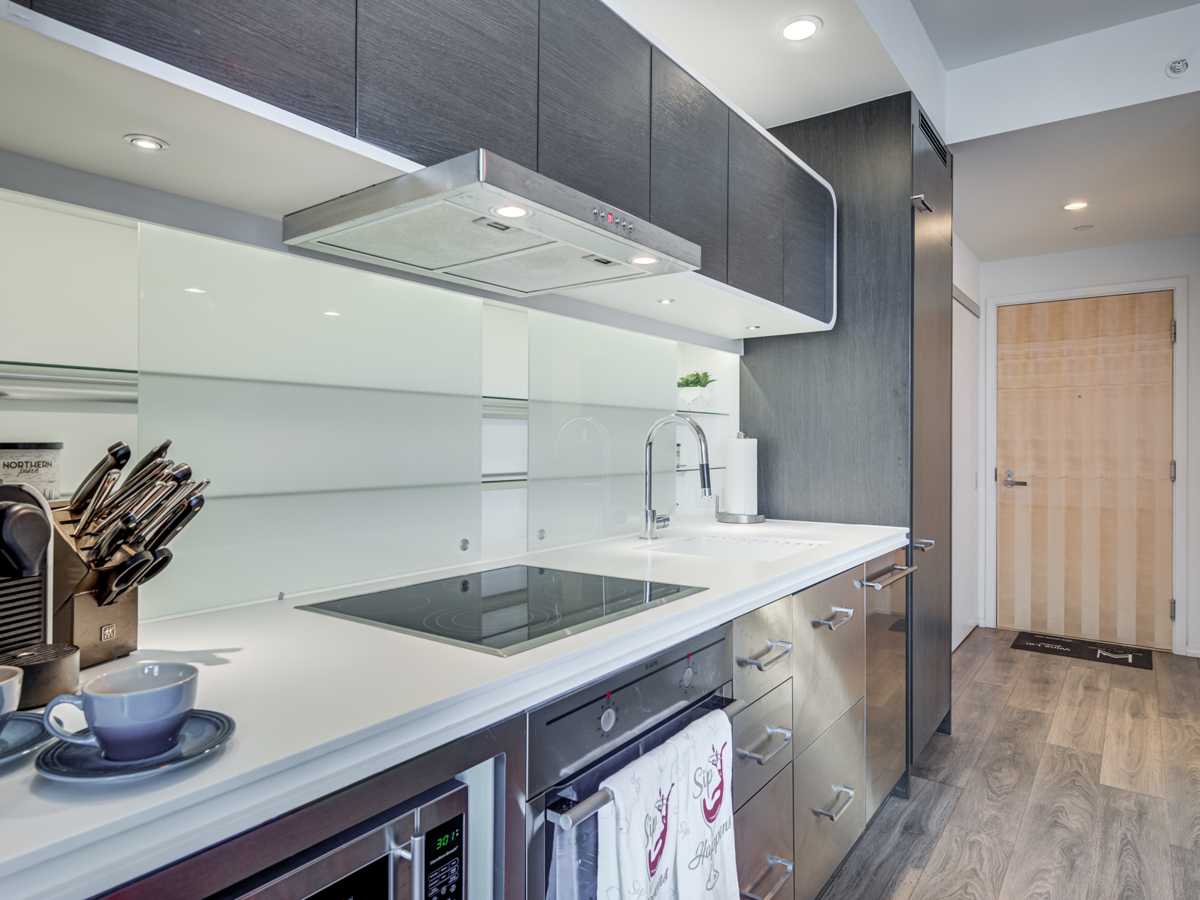 Condo kitchen with stainless steel appliances, dark wood cabinets and dull metal cabinets.