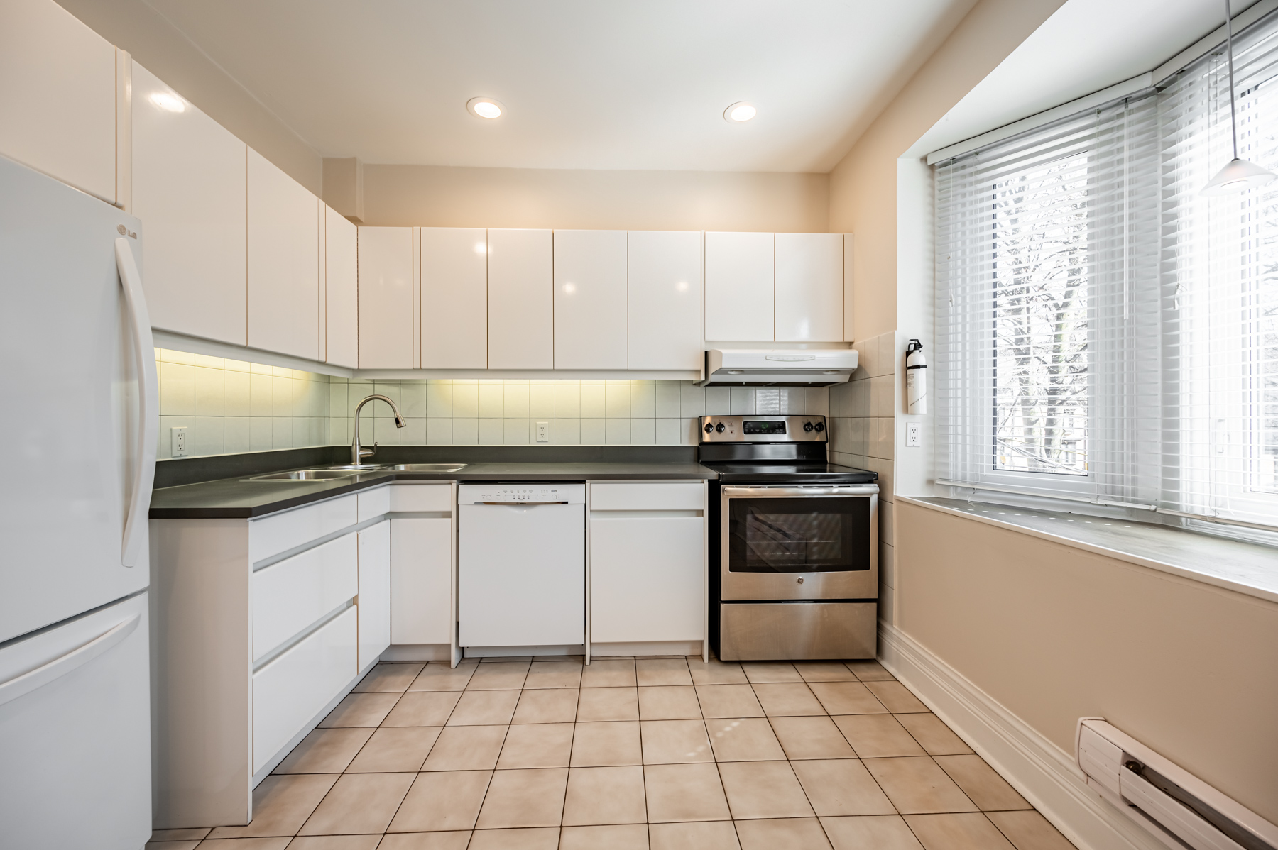 98 Bedford Rd kitchen with potlights, white cabinets, ceramic floors and porcelain backsplash.