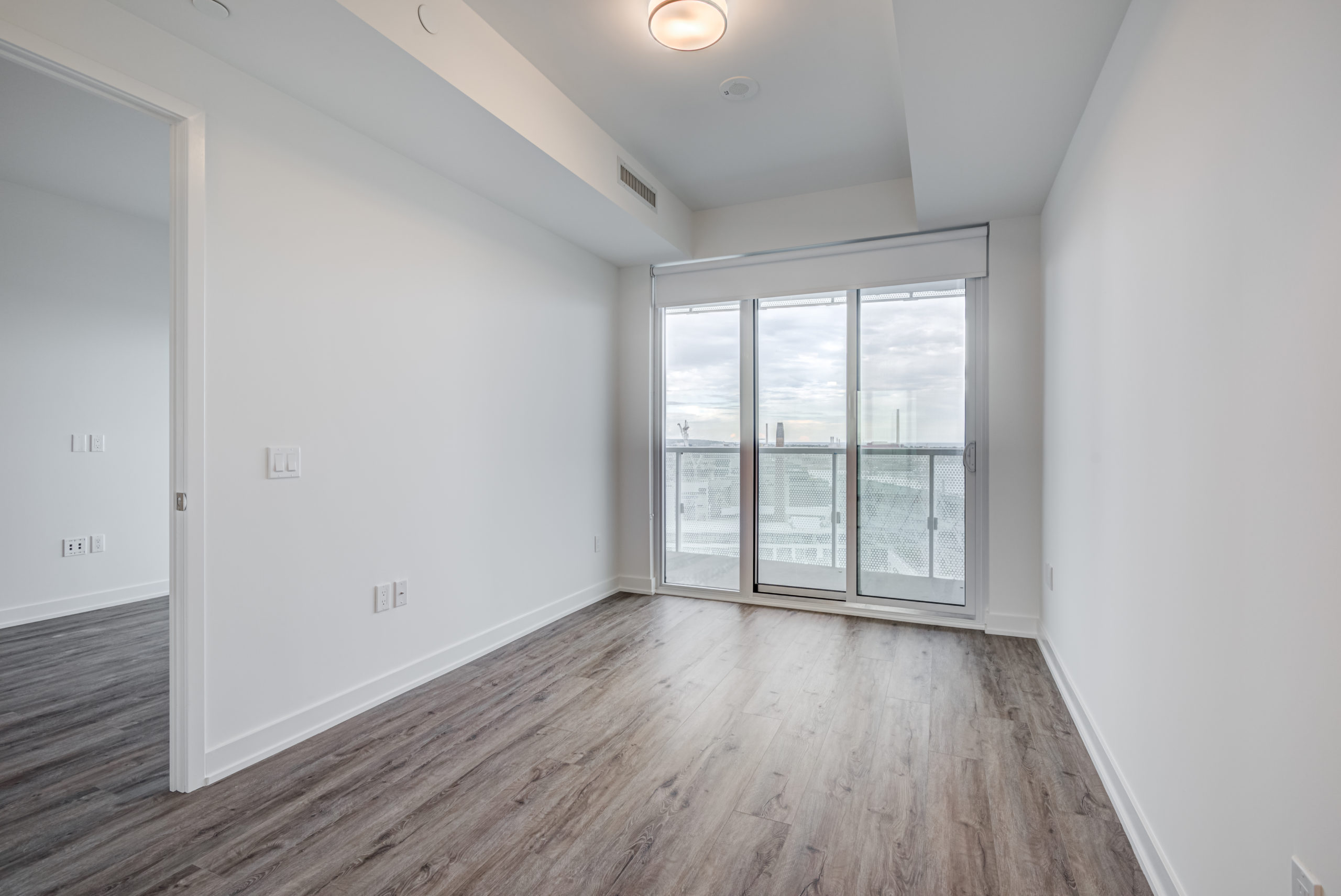 Condo master bedroom with balcony access and Lake Ontario views.