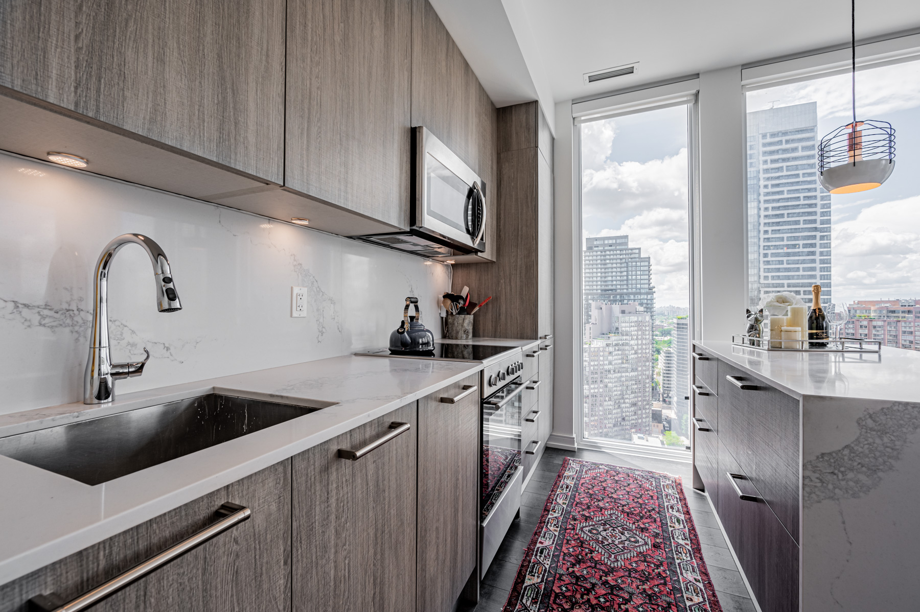 Condo kitchen with quartz counters and matching backsplash.