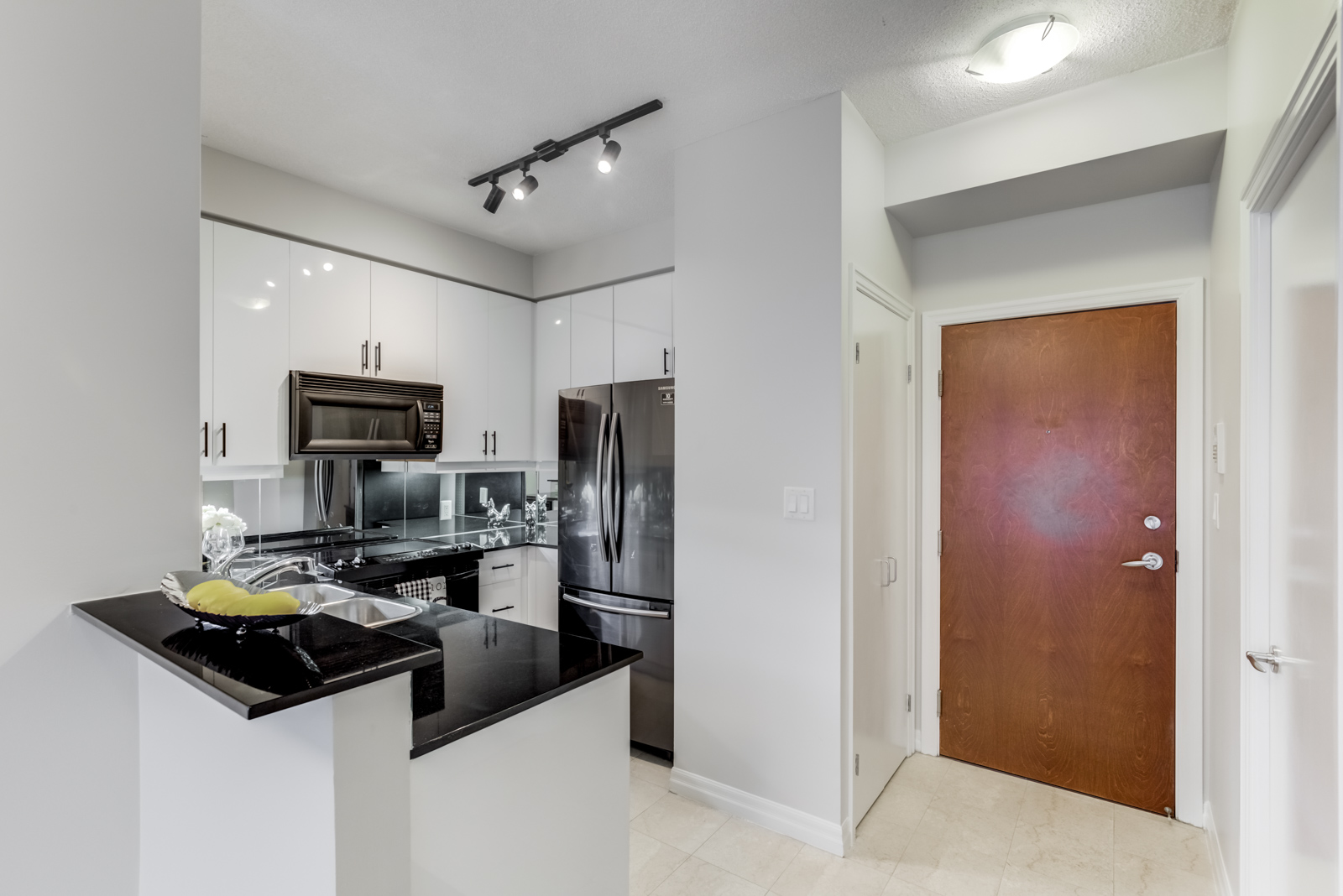 Renovated kitchen of 300 Bloor St E Unit 1809 with centre island, black counter tops and white sides.