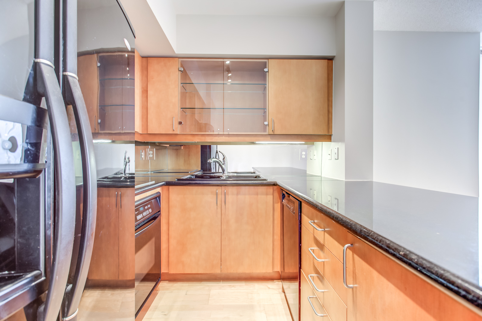 Close up of 20 Collier St Unit 408 kitchen aisle, fridge and bright orange counters and cabinets.