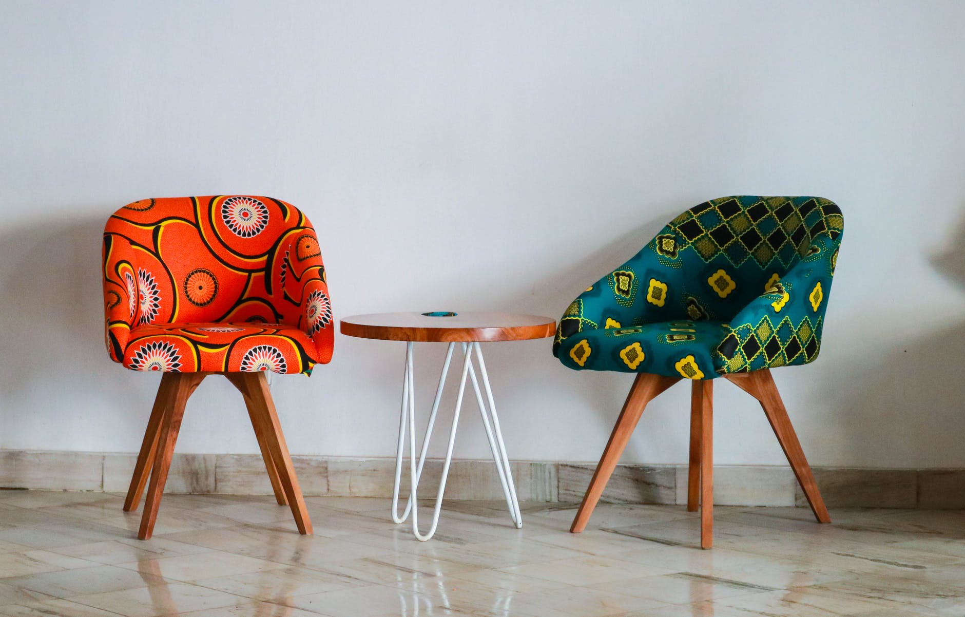 Two colourful chairs and round wooden table. 