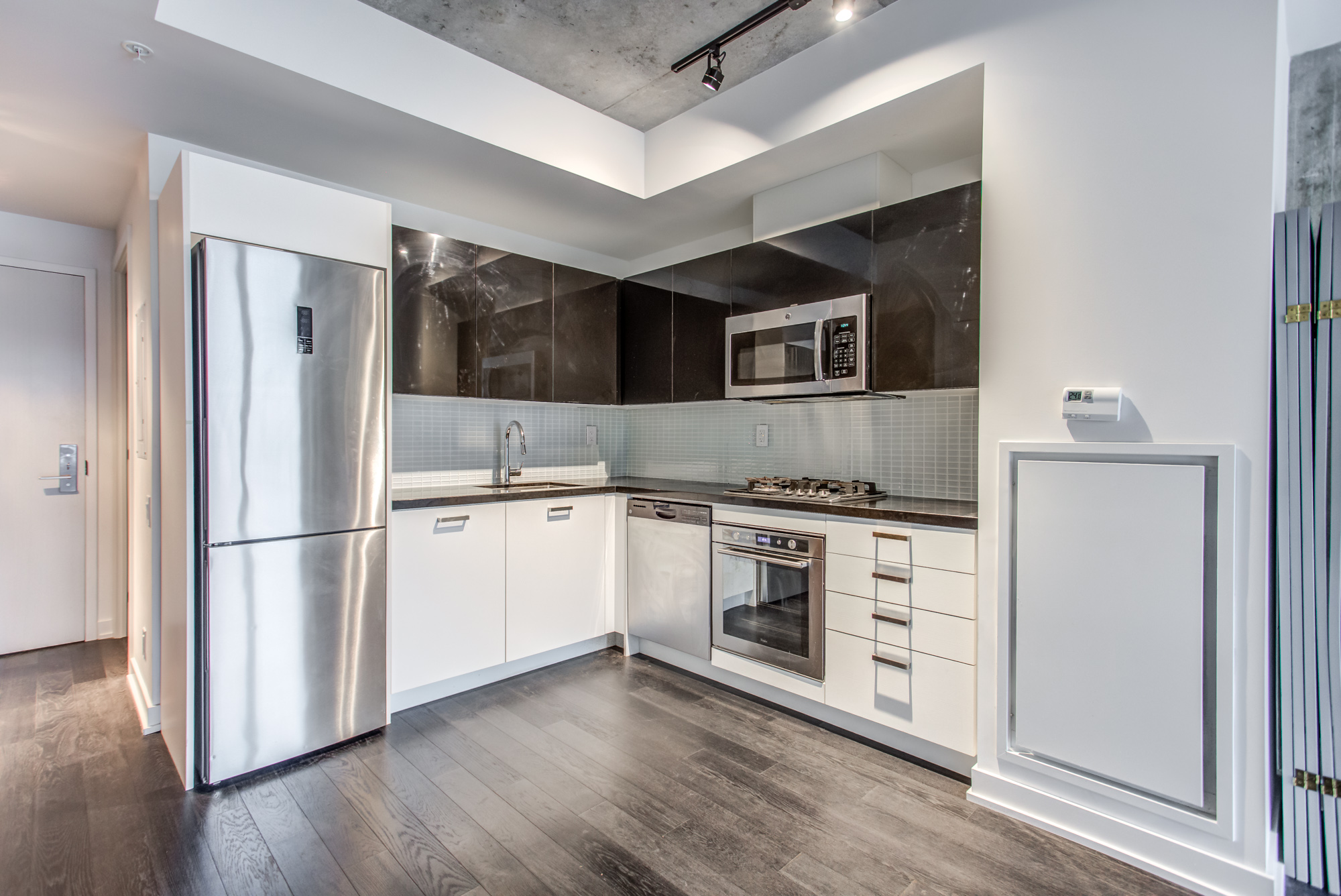 Black and white cabinets and stainless-steel appliances at 39 Brant St Unit 918, Brant Park Lofts, in Queen West.