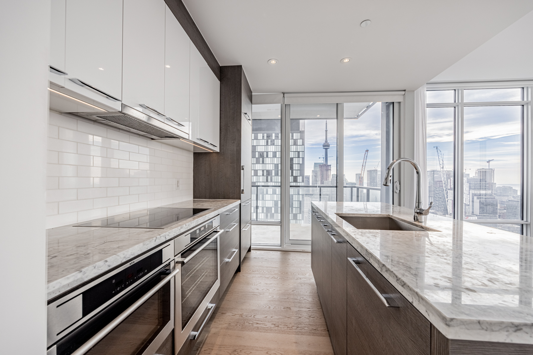 Condo kitchen with under-cabinet lights, tiled back-splash and several cabinets and drawers.