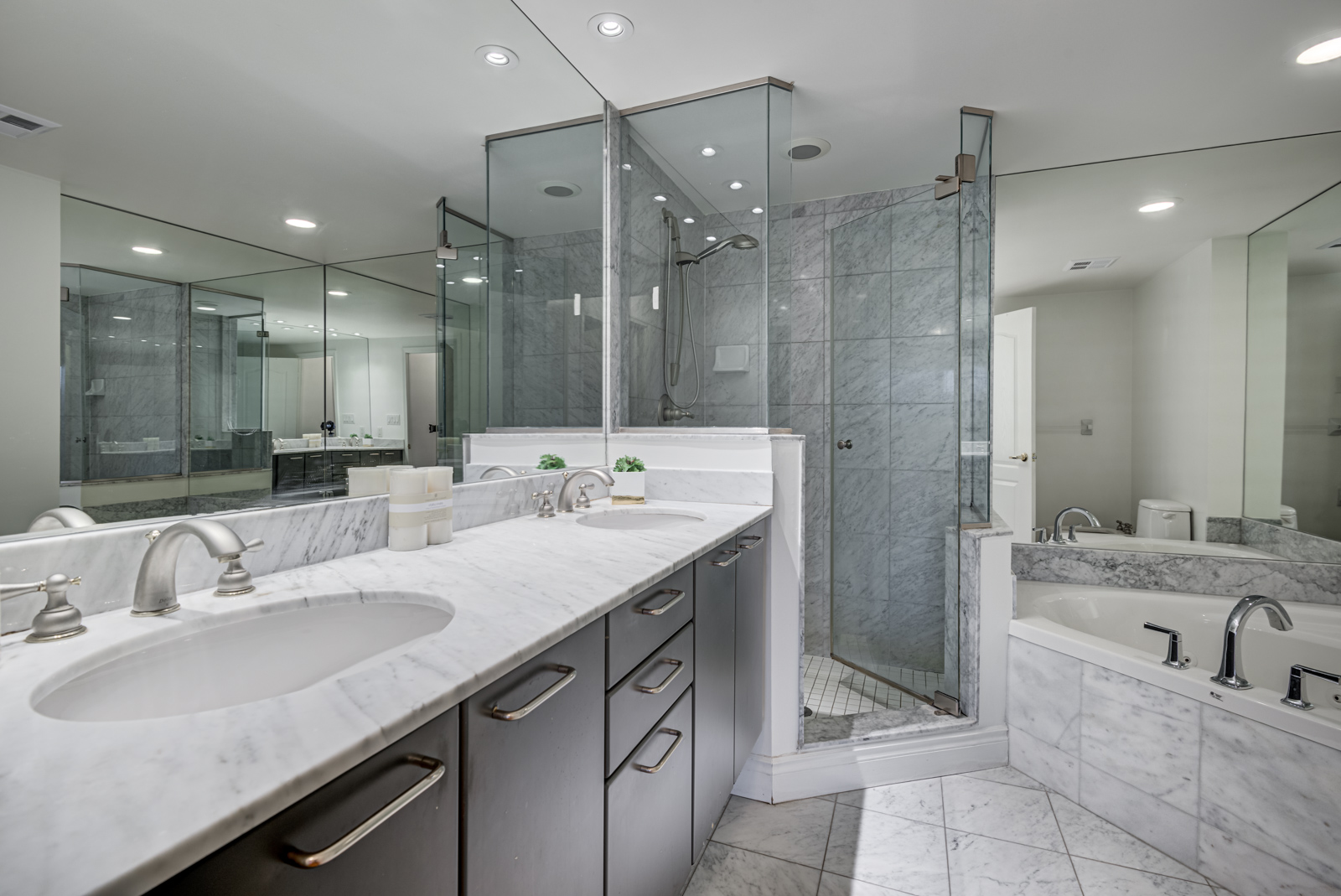 Gray and white master bath with his and her sinks, large tub and glass shower enclosure.