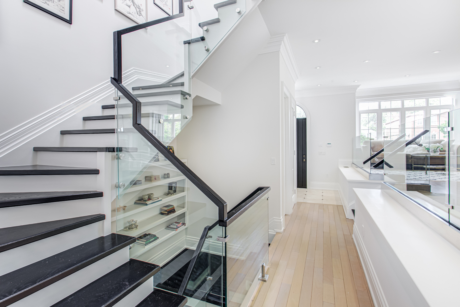 House staircase with black steps and glass rails.