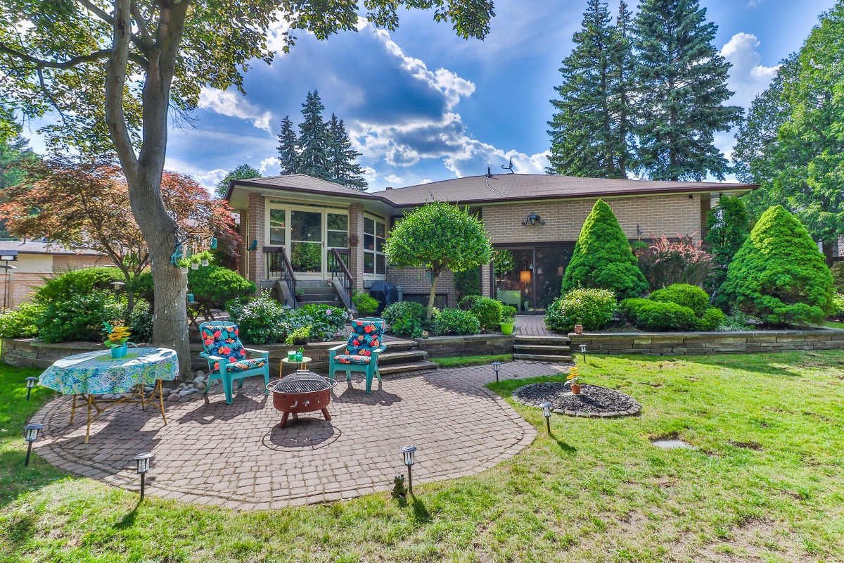 Barbecue set, chairs, table under tree in backyard.