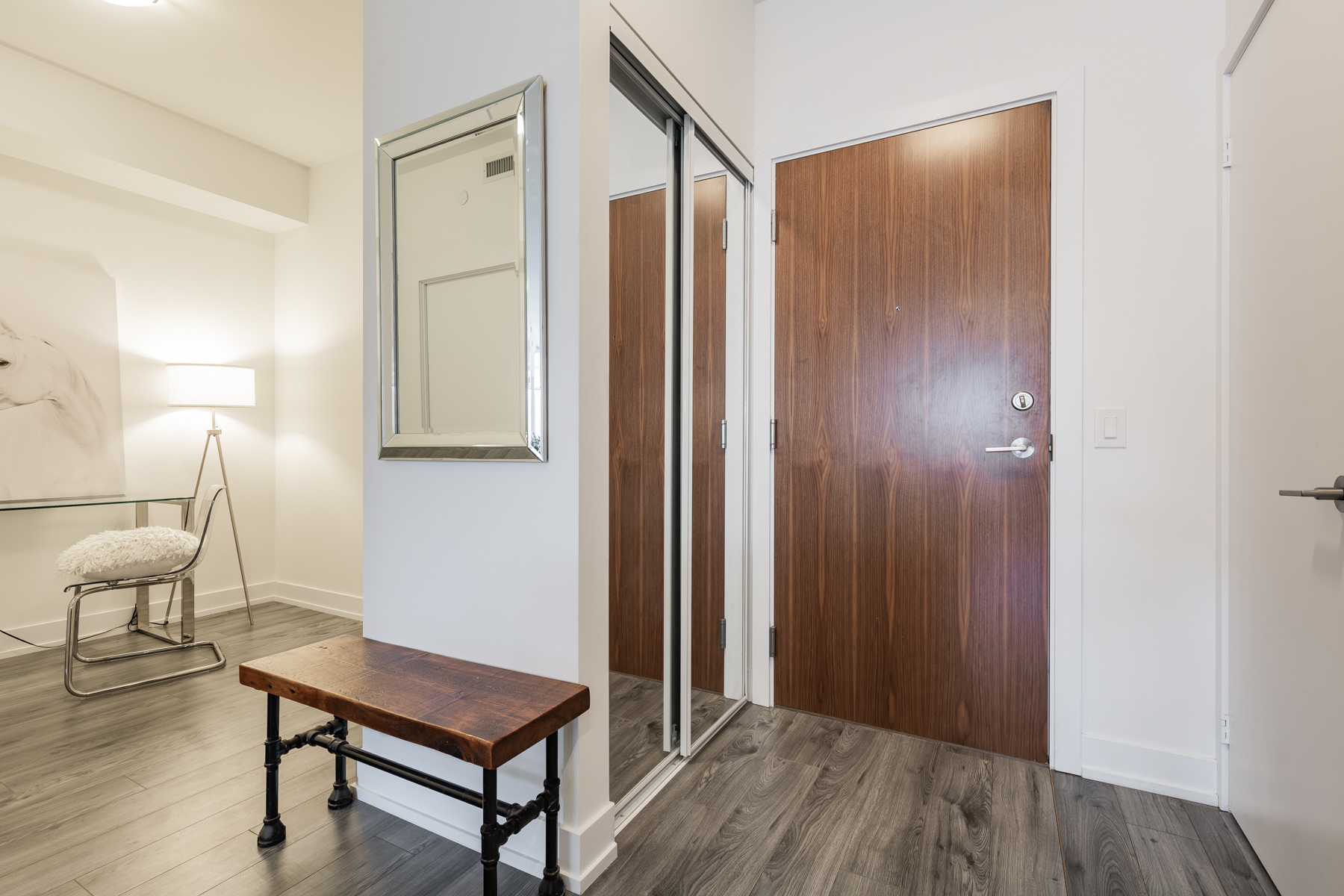 Condo with dark hardwood floors, brown door and light-coloured walls.