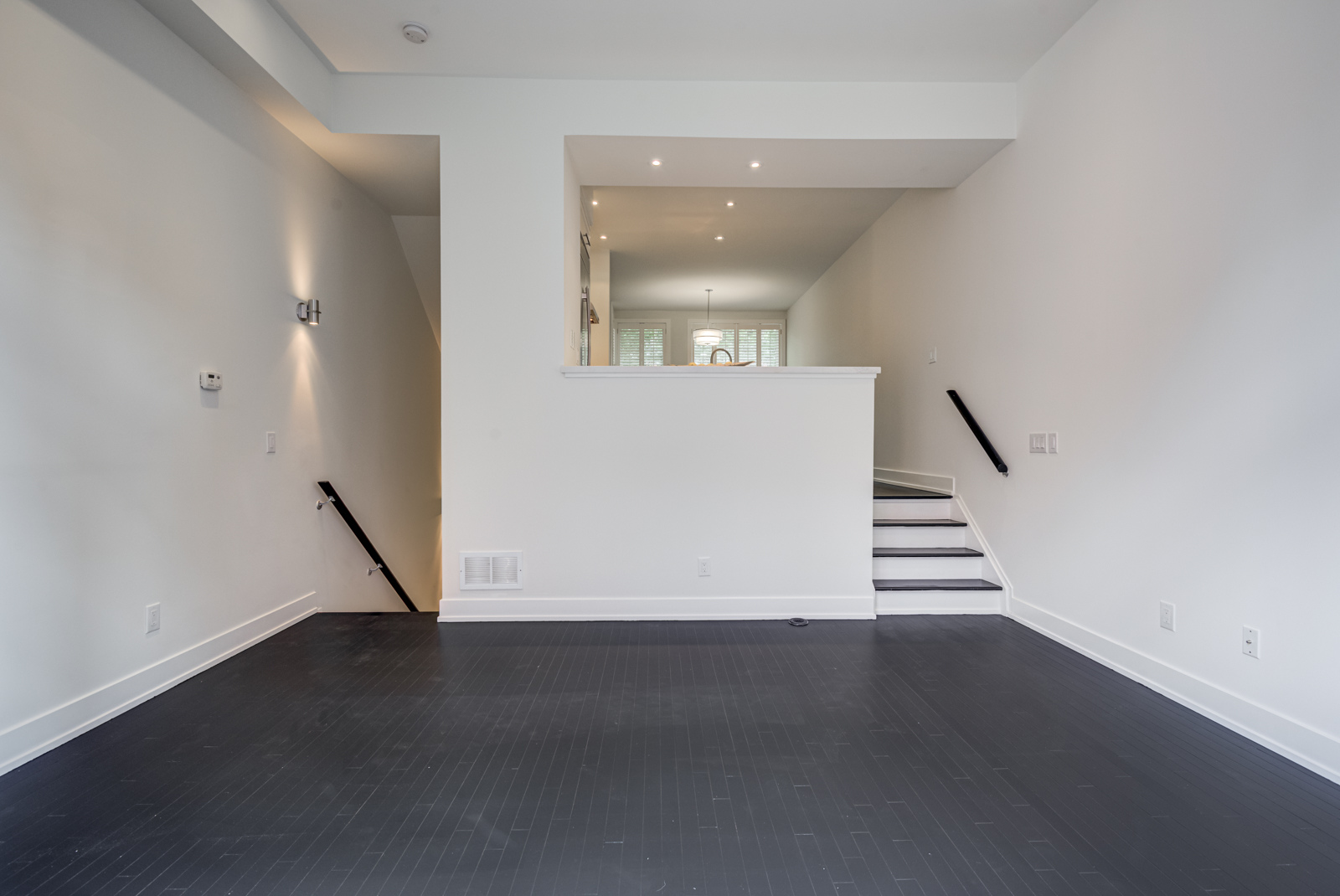 Empty condo with black hardwood floors.