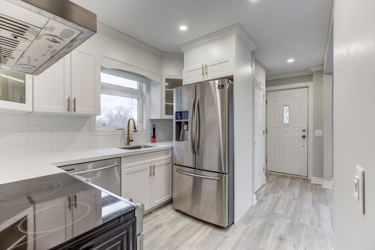 Renovated kitchen with white cabinets, tiled backsplash, laminate floors and pot-lights - 54 Huntington Ave.