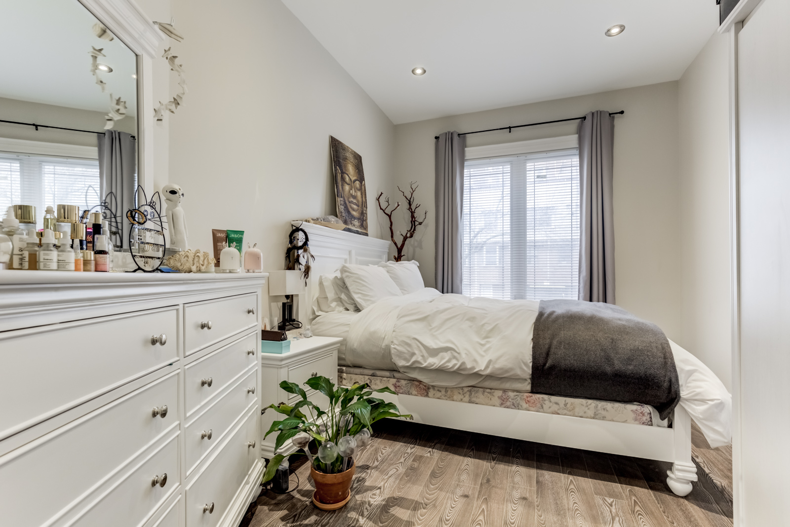 First floor bedroom with large dresser, bedside table and floor plant.