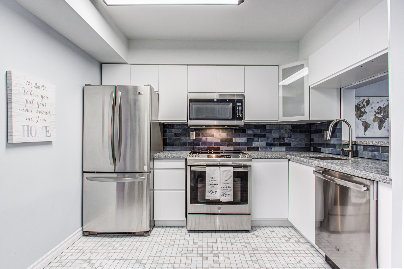Centered view of new kitchen with gray cabinets and stainless-steel fridge, oven and microwave.