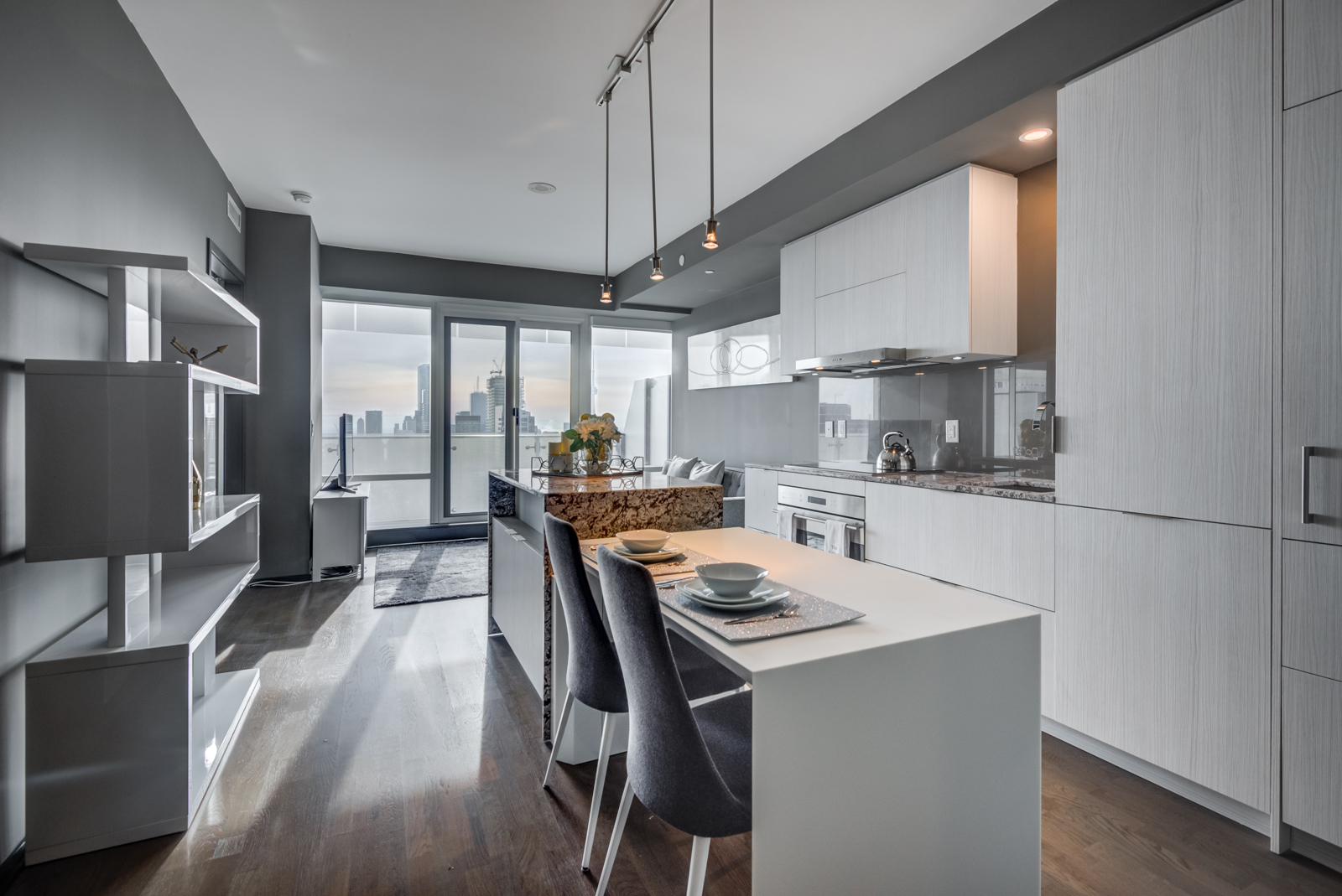 1 Bloor St E Unit 4305 white breakfast bar with two gray chairs and pendant lights.