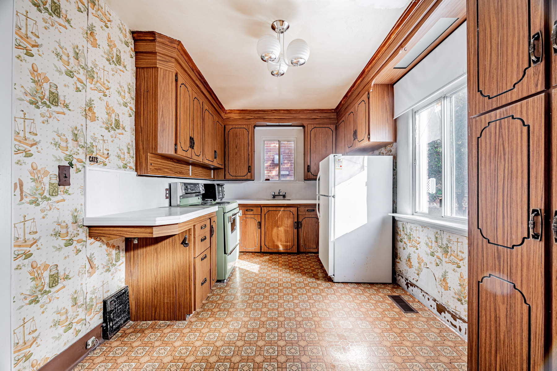 Large kitchen with wood cabinets, 2 windows and stylish light fixture.