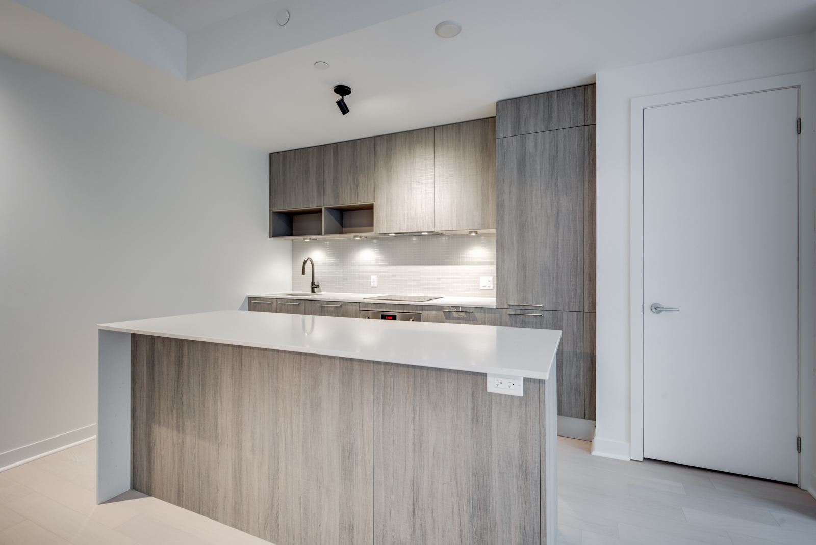 501 Adelaide St W Unit 408 kitchen with brown cabinets, kitchen island with white counters and wooden base.