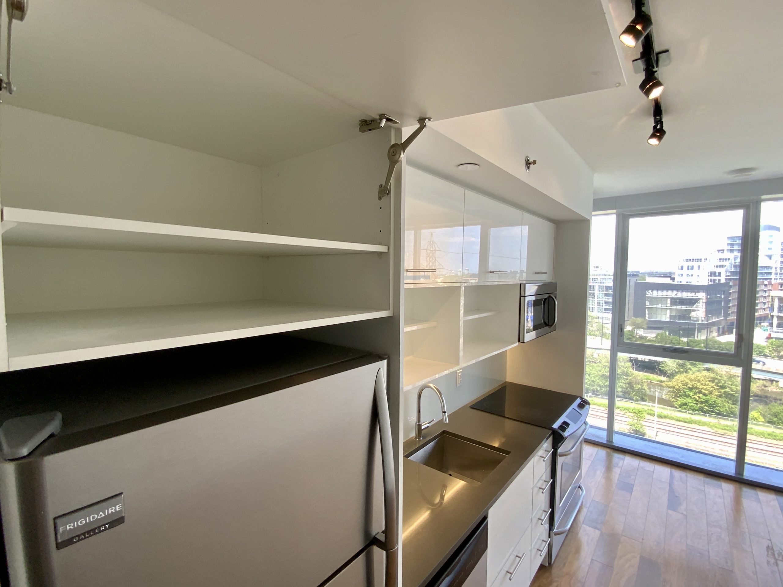 Glossy kitchen cabinets, shelves and track-lights.