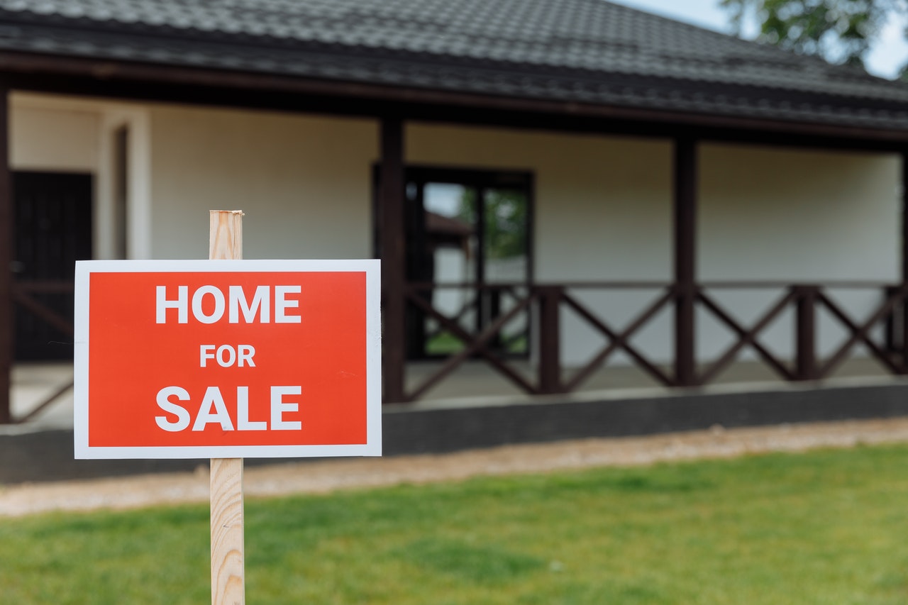 Red and white For Sale sign outside house.