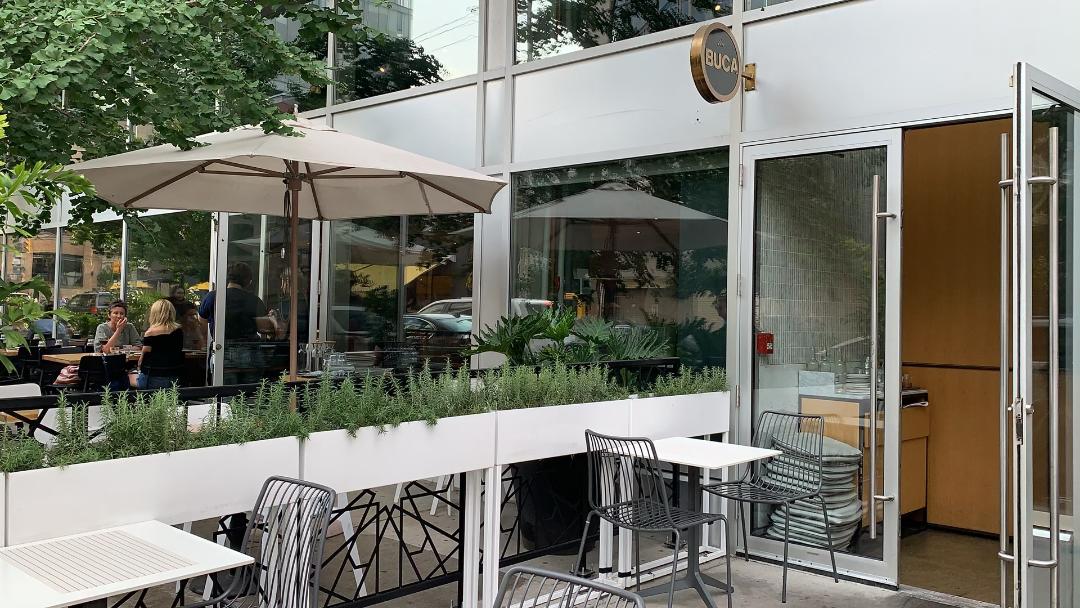 Patio with chairs and tables outside Buca restaurant in King Street West, Toronto.