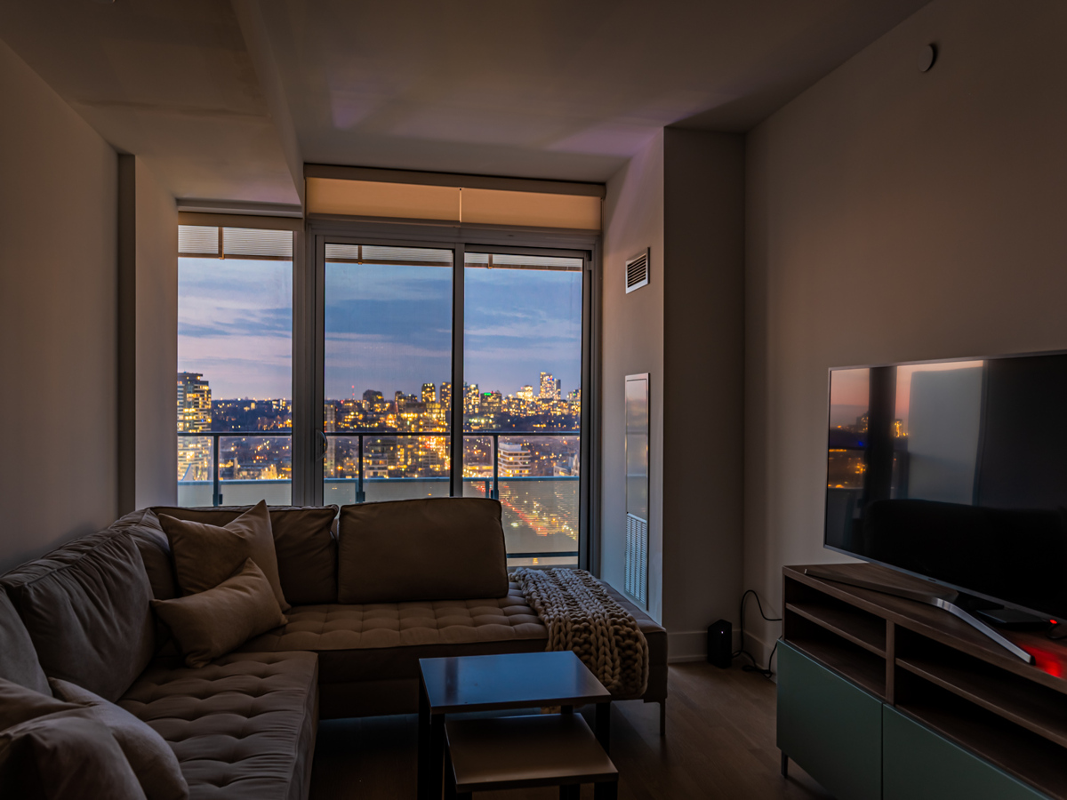 Toronto city lights at night through 200 Bloor St W Unit 2405 balcony doors.