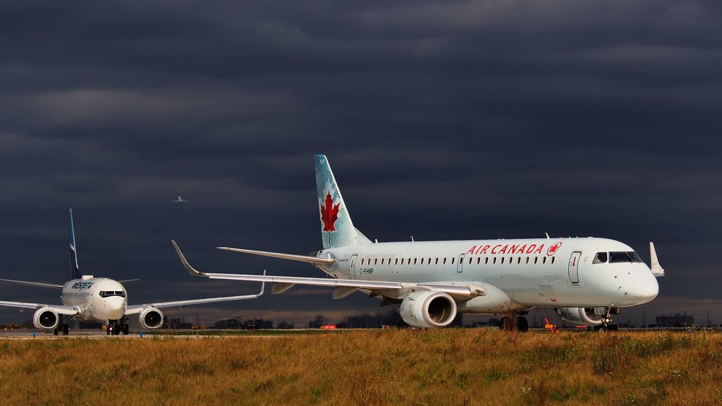 Air Canada plane on tarmac with dark skies above.