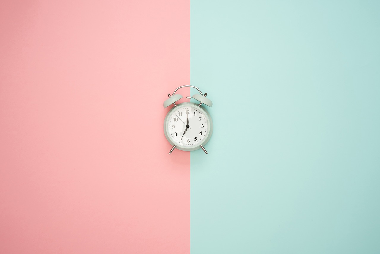 Alarm clock on blue and pink background.
