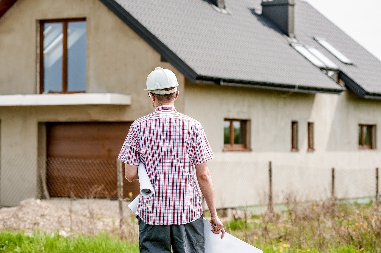 Architect with plans standing in front of house.