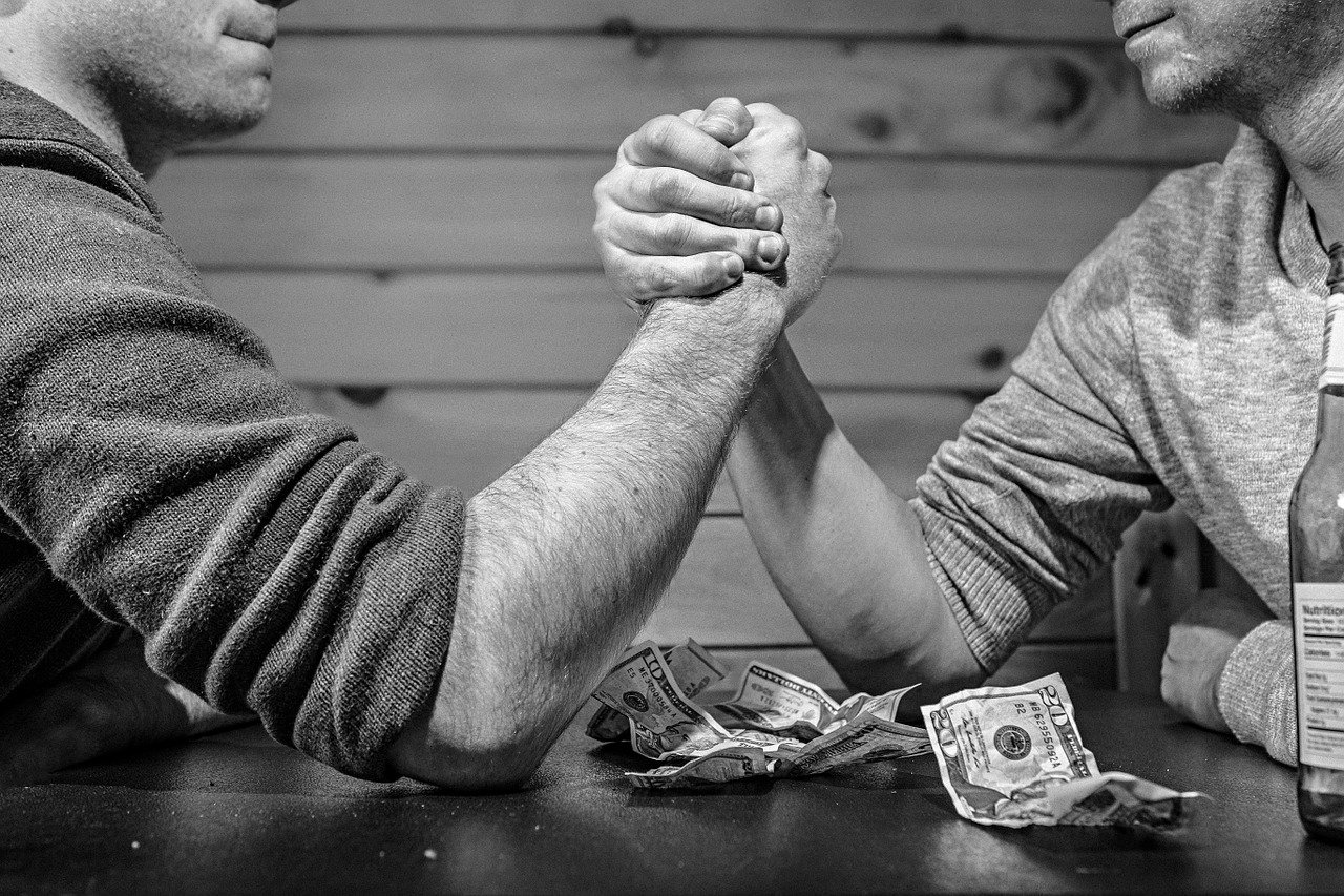 Two men arm wrestling; shows competition for homes in November 2019 GTA real estate market and sellers' market.