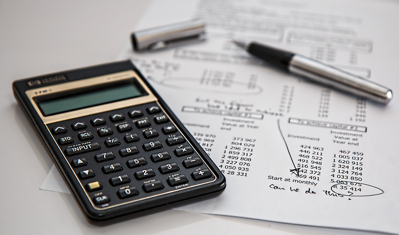 Calculator, pen and paper showing expenses