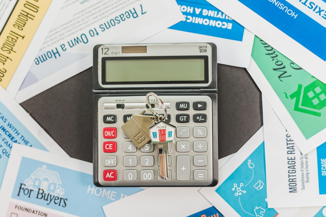 Calculator and house keychain showing rising prices from permanent residency programs.