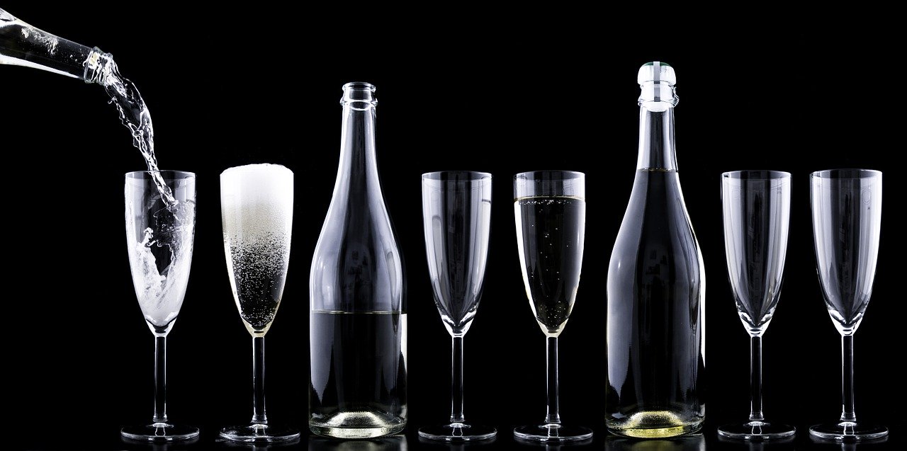 Bottle pouring champagne into neatly arranged glasses.