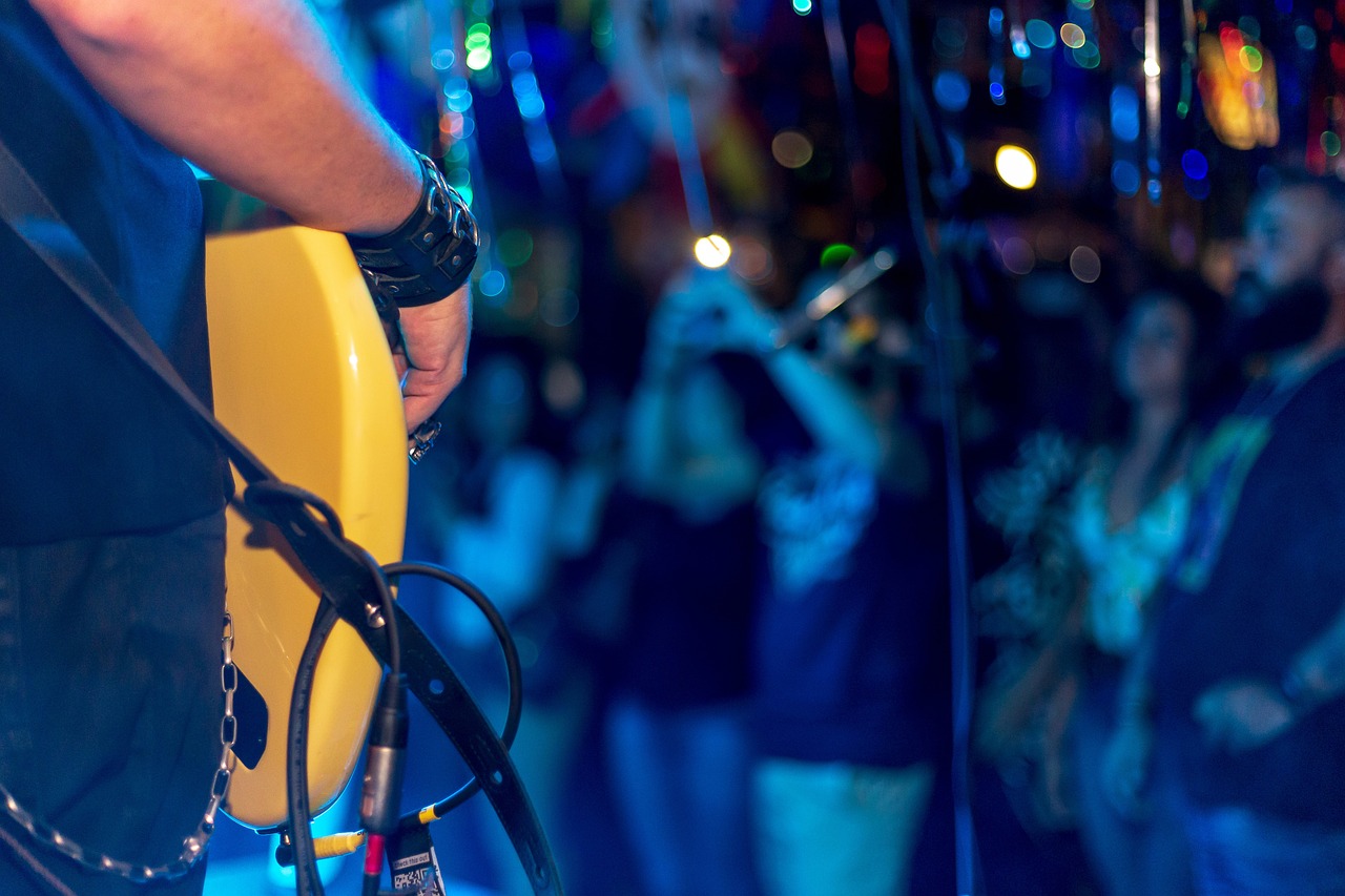 Club with close up of guitar in foreground and people in background. 