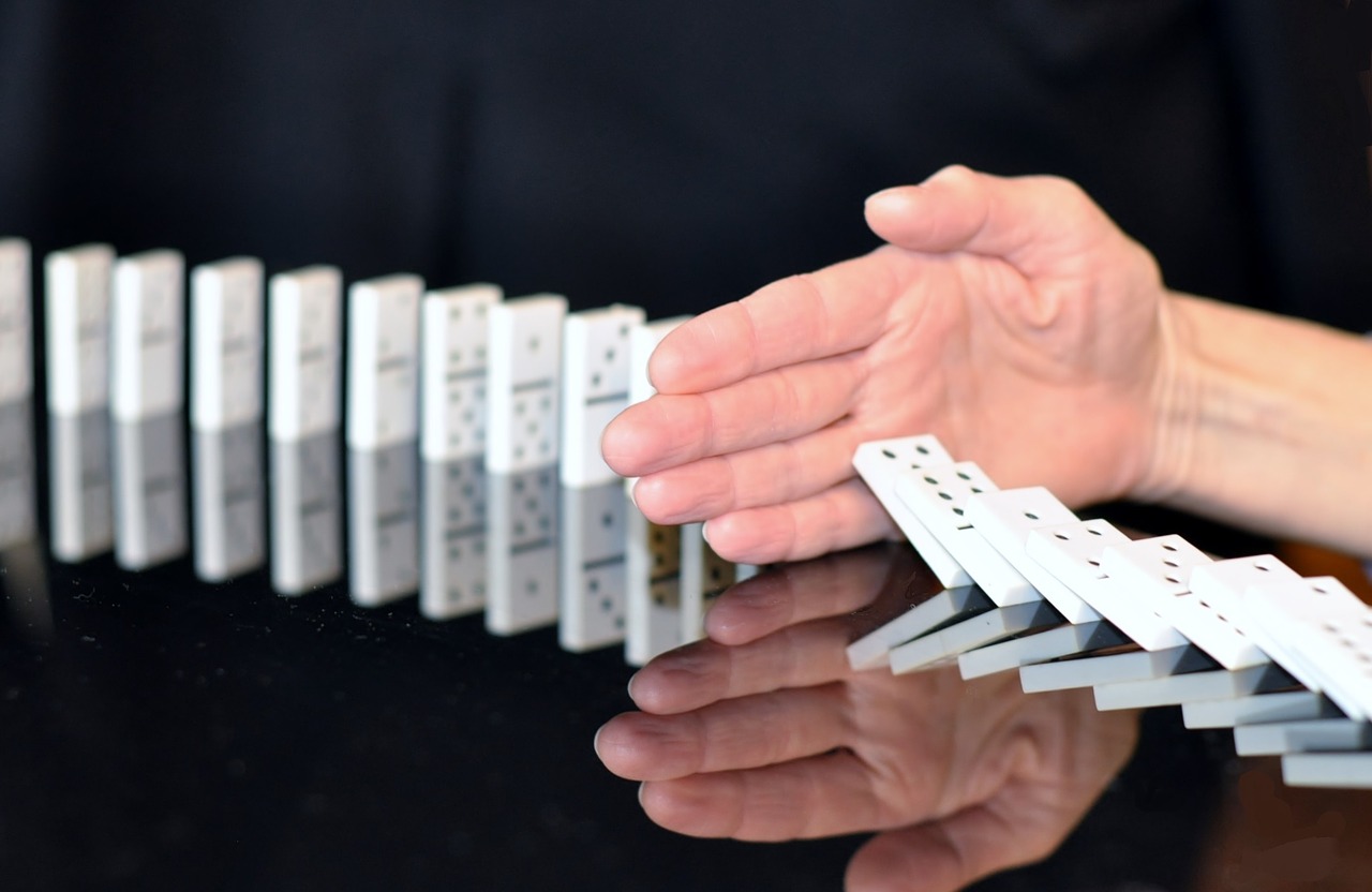 Hand stopping dominoes from falling over.