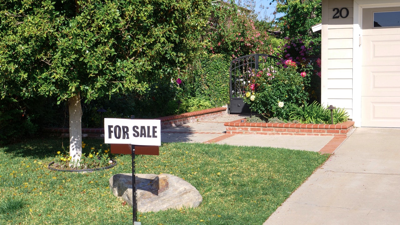 For sale sign on house lawn.