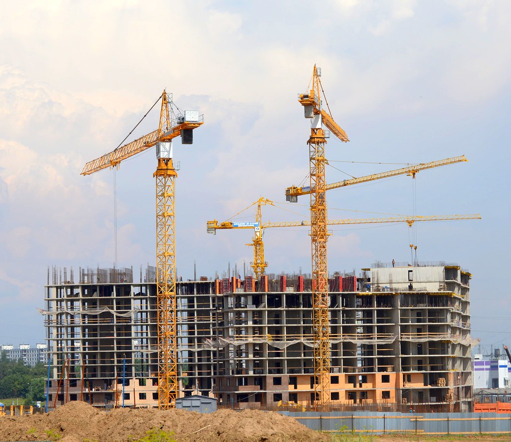 3 large yellow cranes and building