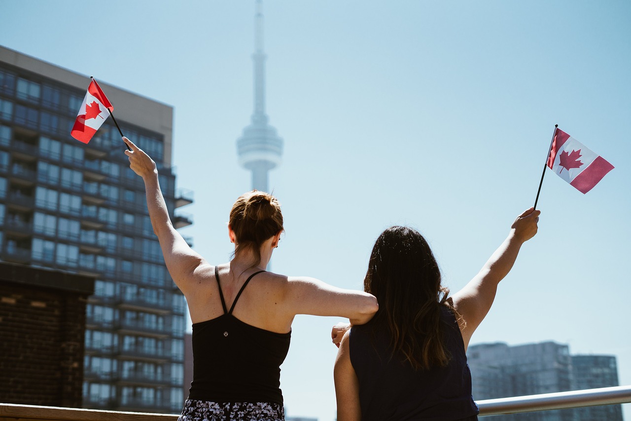 Girls waving Canadian flags in front of the CN Tower in Toronto.