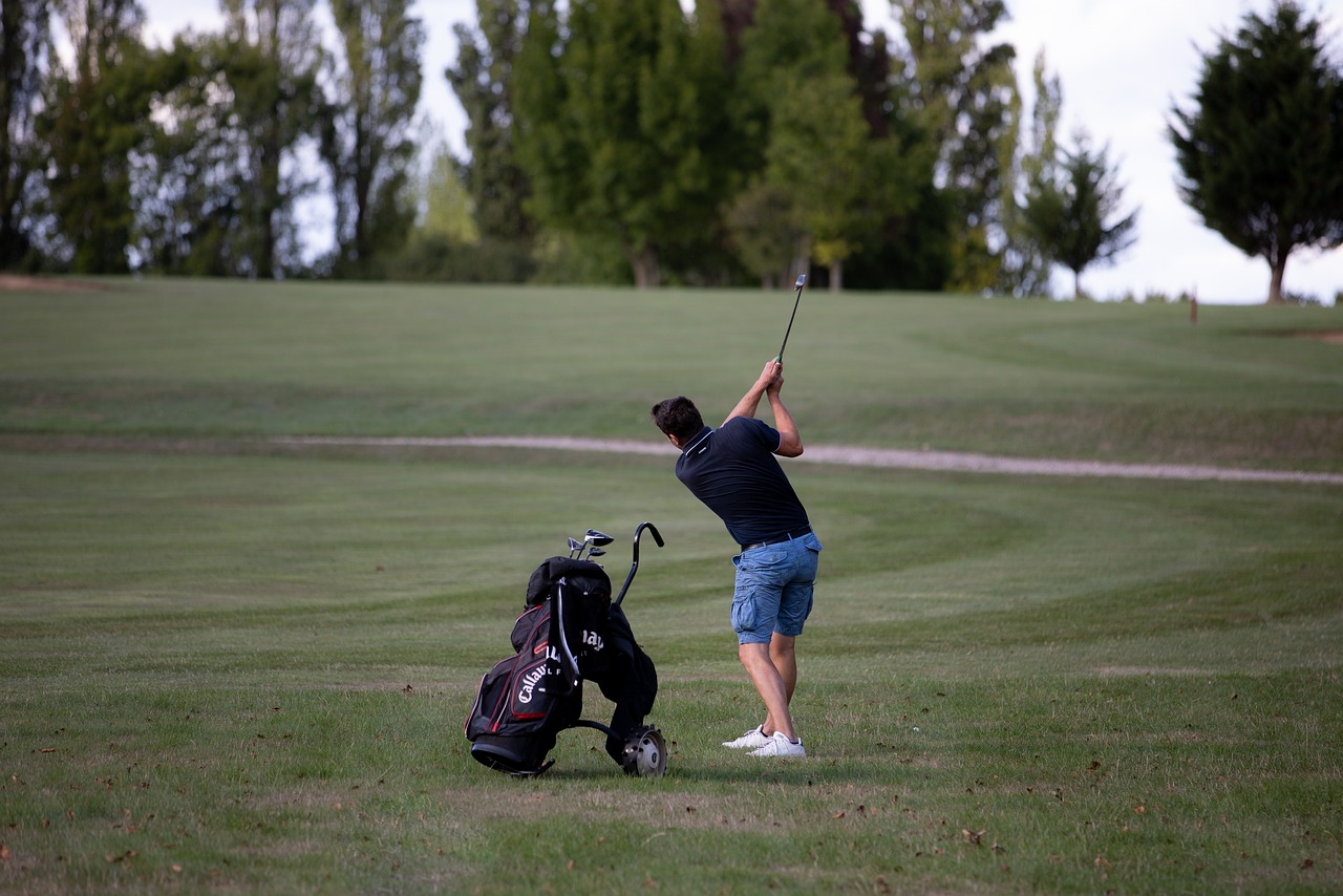 Man swinging golf club with back to camera.