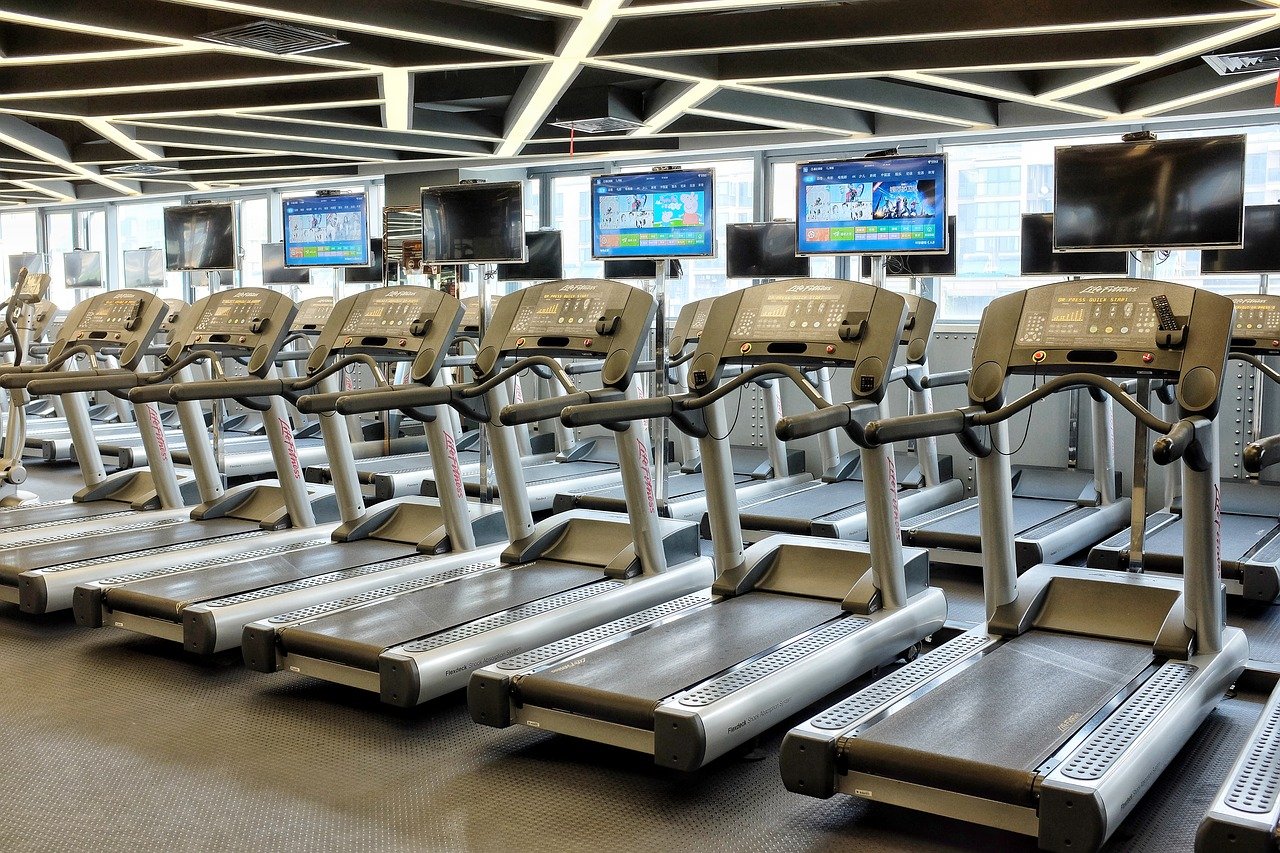 Gym with empty treadmills and TV screens.