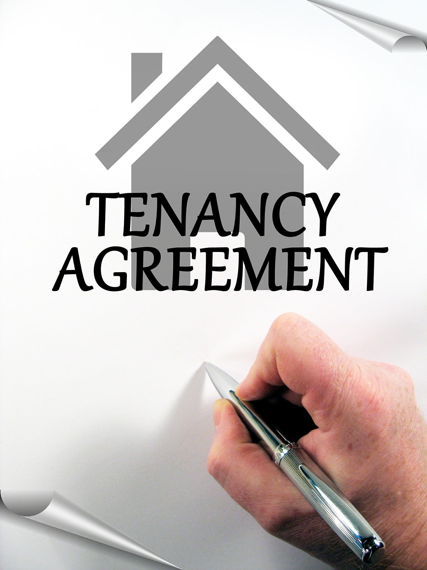 Photo of hand holding pen over a piece of paper saying "Tenancy Agreement." There's a house; best real estate agents in Toronto.