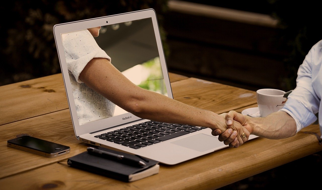 Laptop with hand coming out to shake hands with ask an expert.