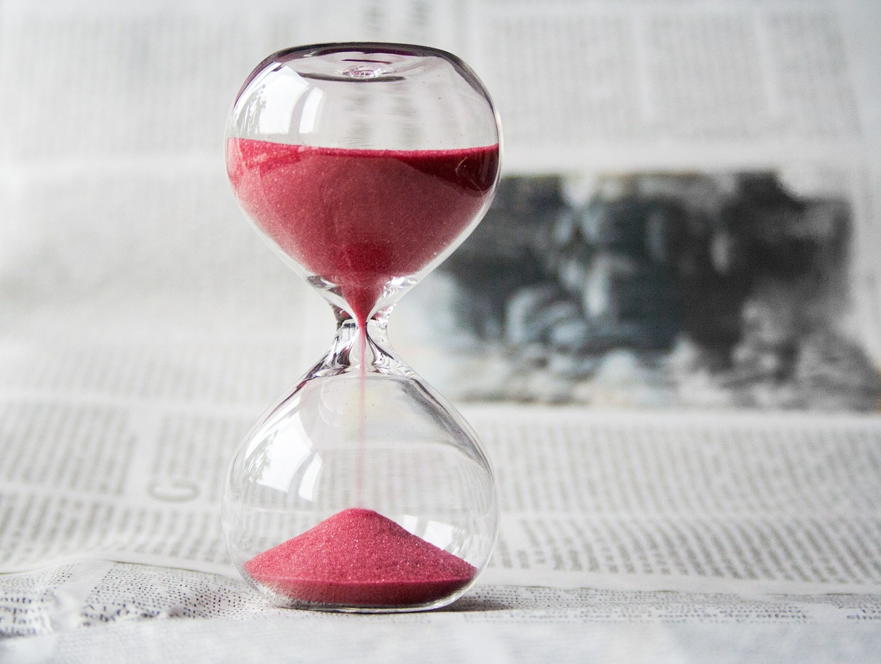 Hourglass with red sand; shows links between time and money.