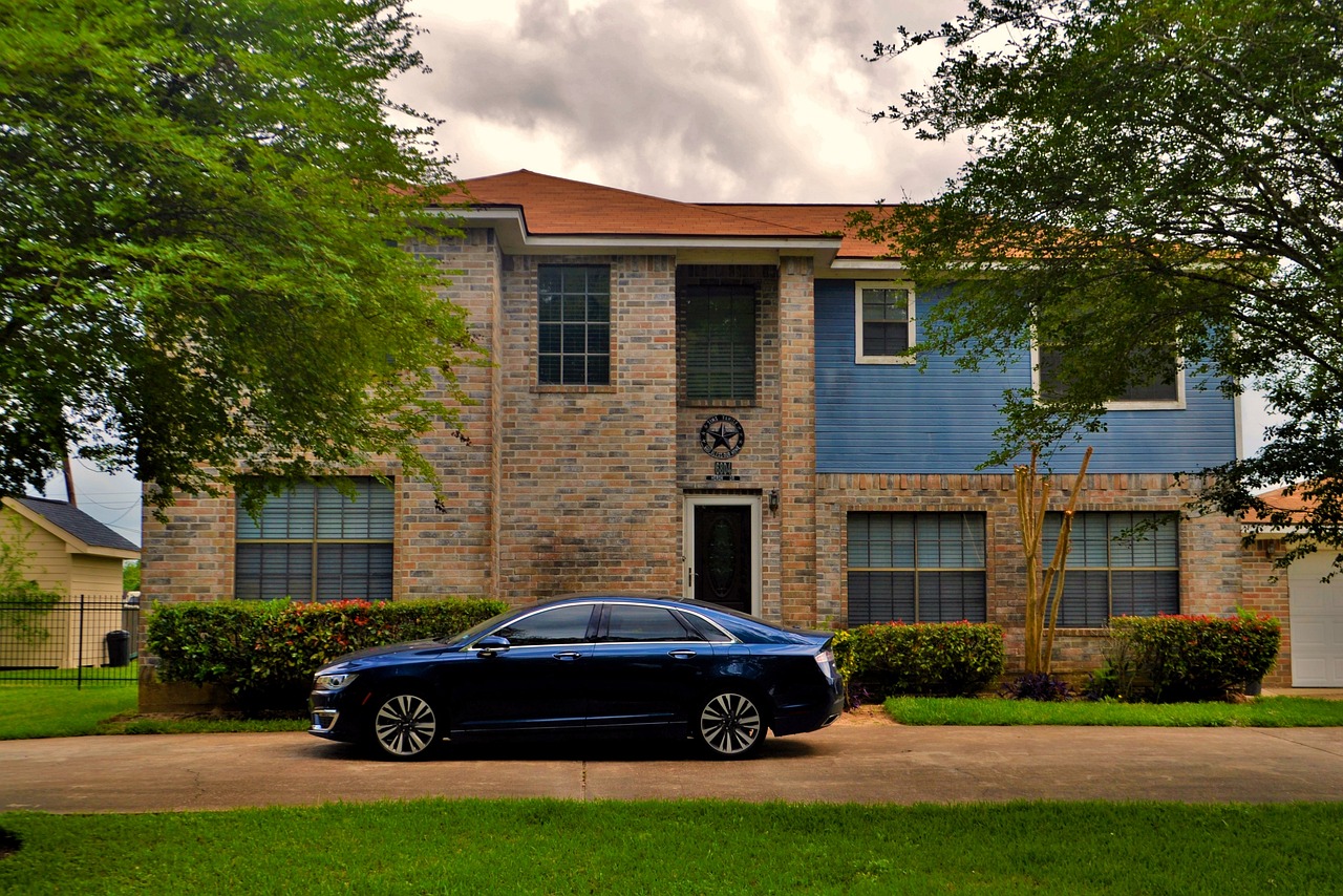 Luxury car parked in front of large house.