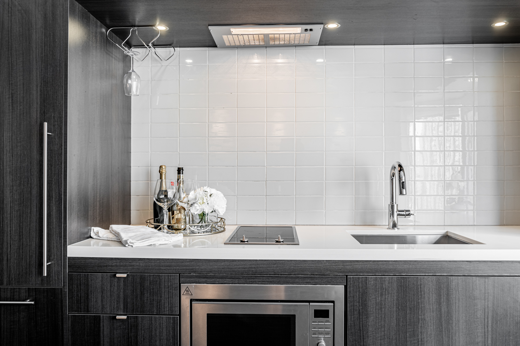 Condo kitchen with dark cabinets, white counters and tiled back-splash.