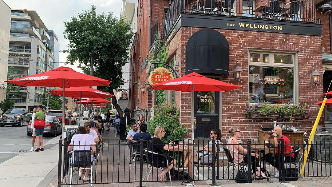 king west toronto wellington bar exterior patio orange umbrellas people