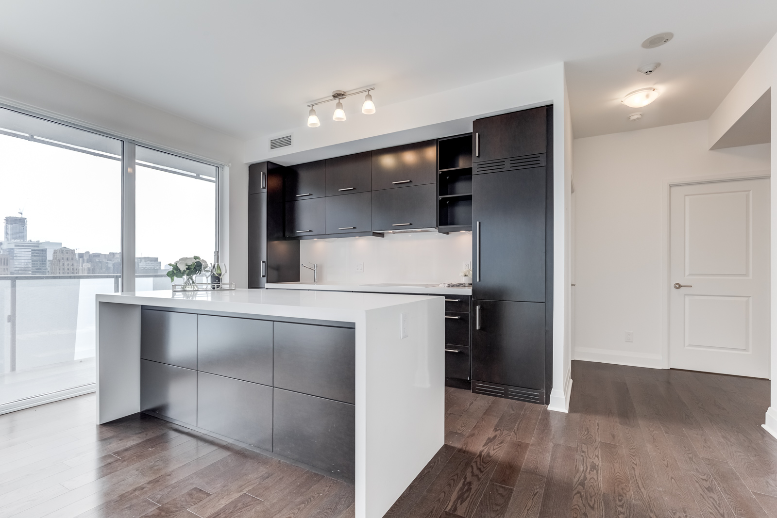 Linear kitchen with dark wood cabinets and silver appliances at 65 St Mary St at U Condominiums.
