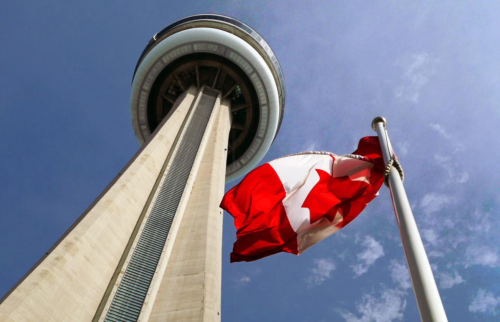 Looking up at CN Tower and Canada flag.